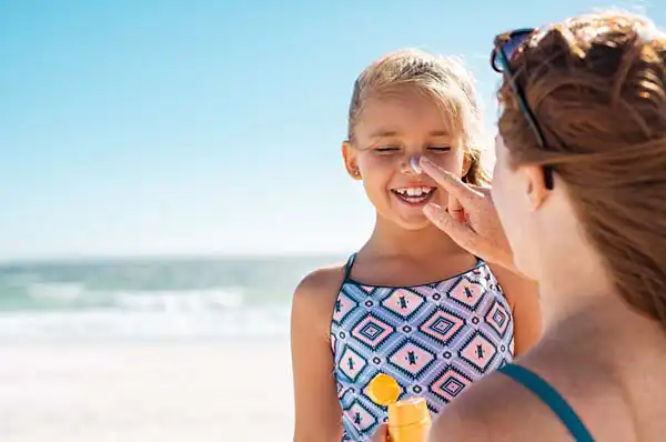 Mężczyzna na plaży aplikuje da przedramiona krem z filtrem